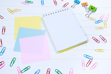 note paper and note book with paper clips on white wooden background