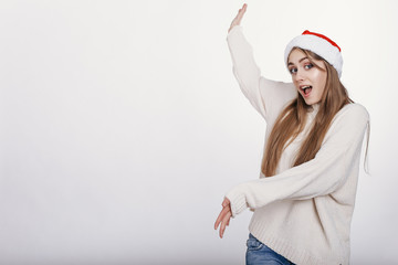 Woman in santa hat pointing on somthing big. Isolated. Copy space. Place for advertising.