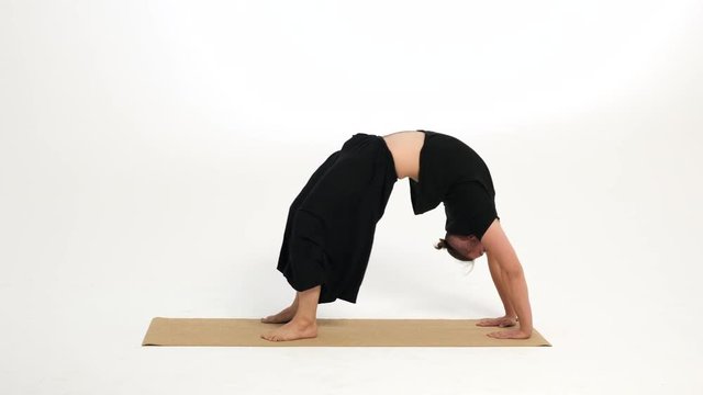 Man demonstrates crab pose / table top pose on a yoga mat against a white background.