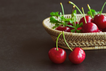 Fresh cherries on wood basket put on black granite table in side view with copy space. Cherry have high vitamin C and have sweet and sour taste. Healthy fruit background concept.