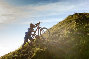 Biker pushes bicycle up in the mountains