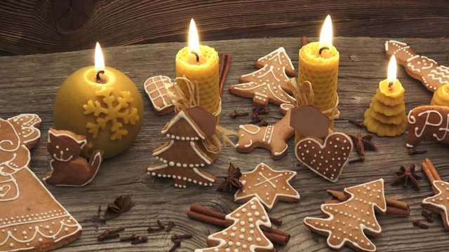 Christmas homemade gingerbread cookies on wooden desk. Yellow scented candles made from natural beeswax.