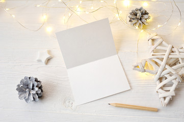 Mockup Christmas greeting card top view, flatlay on a white wooden background with a garland