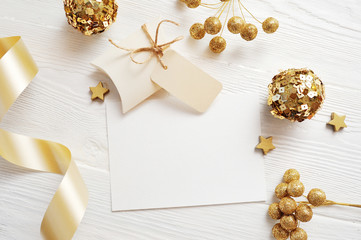 Mockup Christmas greeting card top view and gold ball, flatlay on a white wooden background with a ribbon, with place for your text