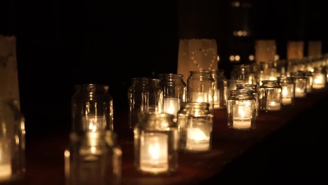 Large group of glass jars with burning candles on the dark background. Advent candle and Hygge concept