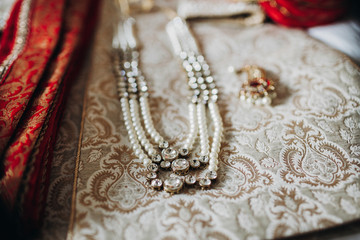 Indian traditional jewerly made od pearls and re precious stones lies on the rich embroidered cloth