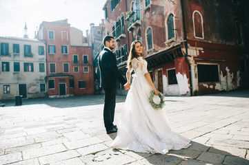 Obraz premium Handsome groom kissing happy bride in street