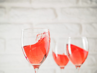 Three wineglass with pink wine on white brick wall background