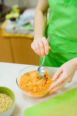 white caucasian woman mix with a spoon in a glass bowl carrots, egg and flax seeds