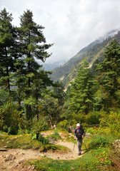 Man with hiking equipment walking down on mountain trail during a hike.