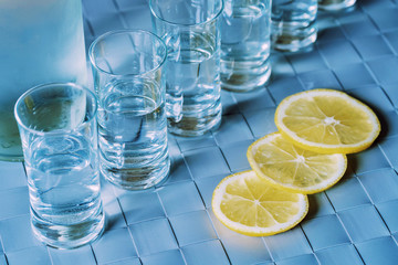 Vodka shot glass and lemon on blue surface