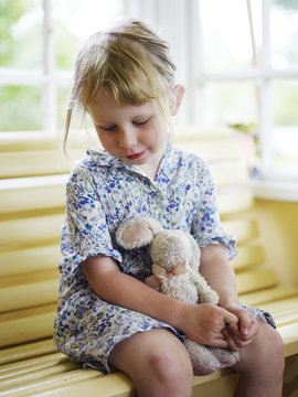 Scandinavia, Sweden, Girl  sitting with soft toy, close-up