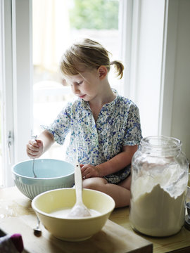 Scandinavia, Sweden, Girl  mixing ingredients and flour in bowl
