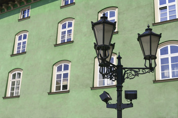 Fototapeta na wymiar Street lamp in front of green-wall windows