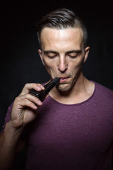Man on black background vaping and releasing a cloud.