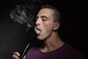 Man on black background vaping and releasing a cloud.