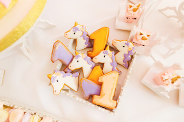 Obraz premium cookies in the form of unicorn and mini cakes on a white tablecl