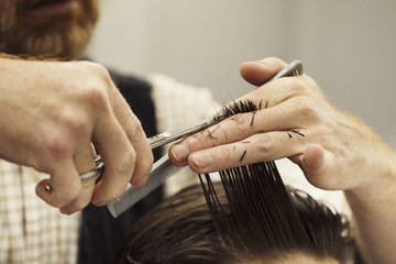 A hairdresser cutting a man's hair, close up.