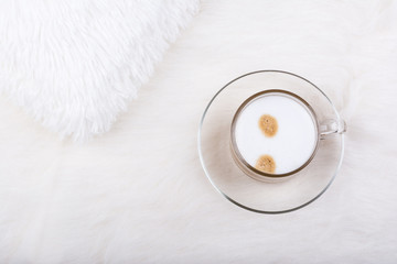 Top view of cup of latte coffee on white furry carpet.