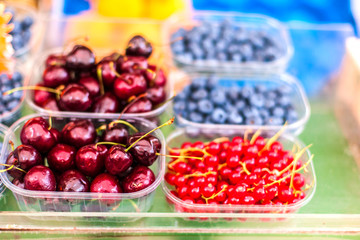 Fresh boxes of assorted berries on display at farmers market. Healthy local food  concept. Variety of berries .