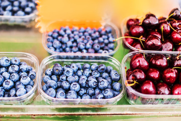 Various berries from a local farmer market.  Healthy local food market concept. Variety of berries in a box -  blackberry, raspberry, strawberry, cherry.