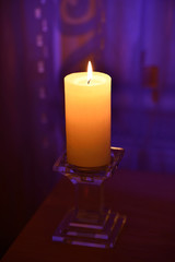 One candle flame in front of purple background