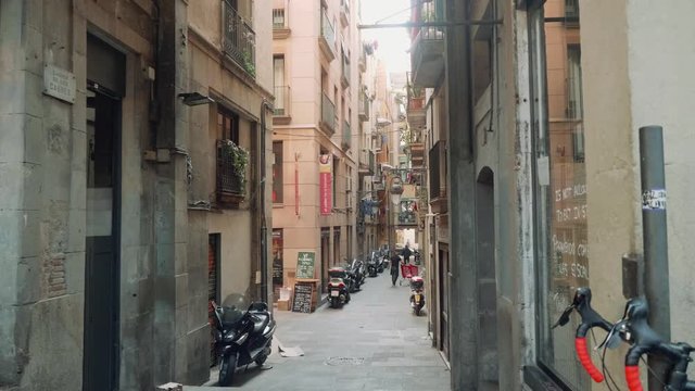 Narrow street of gothic area with scooters parked and some people walking