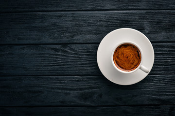 A cup of espresso coffee on a dark wooden background. Top view. Free space for text.