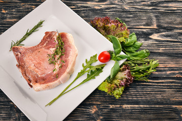 Raw veal steak on a plate. On a wooden background. Top view. Free space for text.