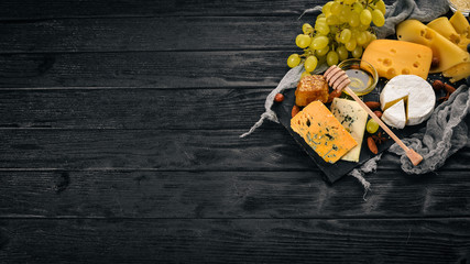 Grapes, red wine, cheeses, honey and nuts on a wooden background. Top view.