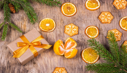 Obraz na płótnie Canvas Christmas decorations with fir tree, gift box, cookies, snowflakes and tangerine. Gift box with golden bow.