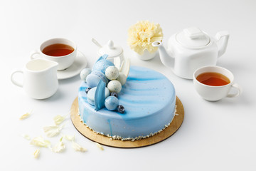 blue tasty cake on chopping board with tea and flower isolated on white