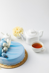 Obraz na płótnie Canvas blue tasty cake on chopping board with tea and flower isolated on white