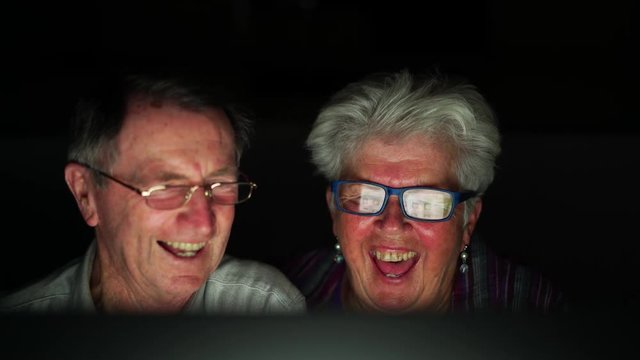 4k video happy smiling laughing senior couple sitting together in front of computer talking to friends viy skype during evening at home
