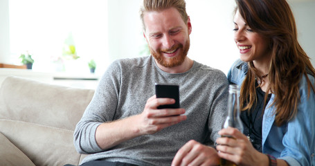 Relaxed couple or friends using mobile phone together to shop online