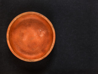 Empty clay plate on black background