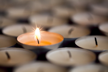Selective focus on magical light from a single sparkling flame from one candle among many...