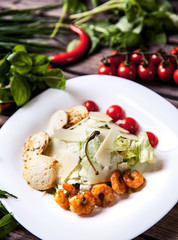 Salad with meat, cheese and tomatoes on a wooden background