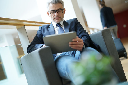 Businessman in airport waiting area connected with tablet