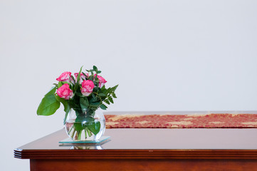 Empty room interior with white walls and wooden desk with flowers