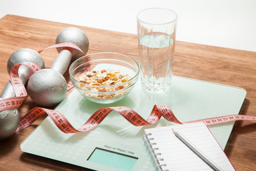 Healthy diet, fitness and weight loss concept. Scales, measuring tape, weights, oatmeal and a glass of water on the table.