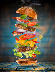 Big tasty burger with flying ingredients.