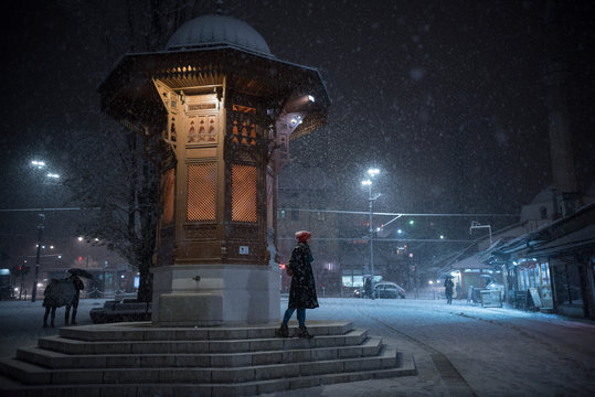 Sebilj in Sarajevo on snowy night and girl walking down the steps 