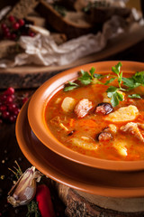 Traditional Russian and Ukrainian cuisine, lunch, first course, red soup in a clay dish on a wooden table