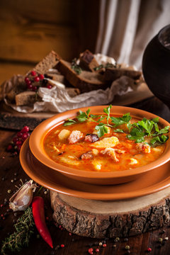 Traditional Russian and Ukrainian cuisine, lunch, first course, red soup in a clay dish on a wooden table