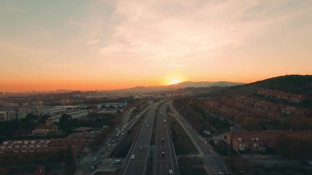 Beautiful aerial shot on sunset in mountains above highway with many cars driving fast in both directions. Scenic image of modern life with stopless motion