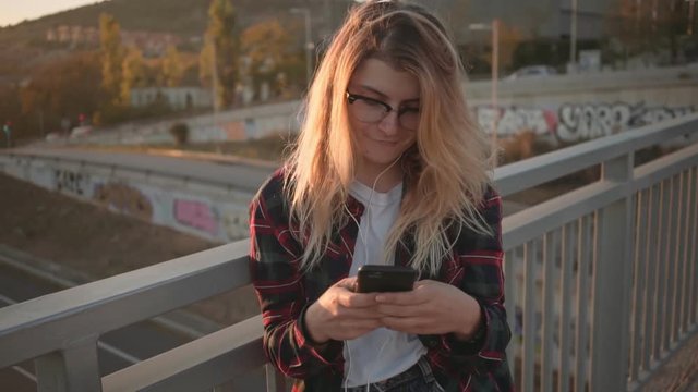 Slow motion portrait of beautiful natural cute and pretty young woman, text and chat on smartphone with friends and followers, trendy millennial social media influencer smiles and blogs