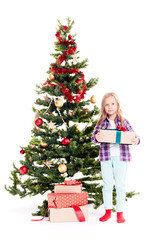 Portrait of little girl standing near Christmas tree with gift box in her hands on white background