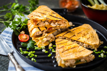 Mexican food quesadilla with grilled chicken, salsa and cheese, with greens and vegetables