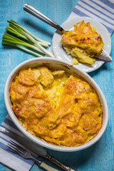 potato gratin with cream and Parmesan cheese on a blue background